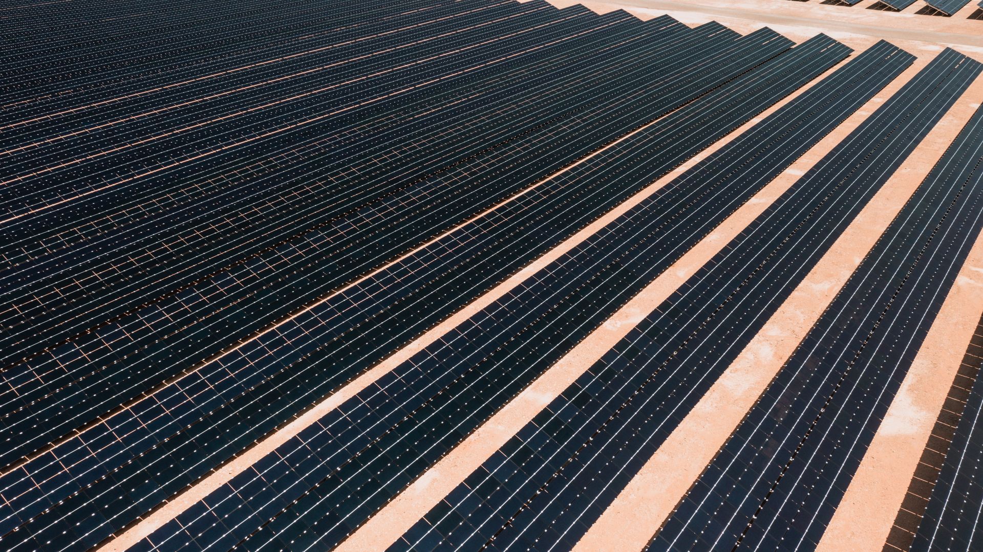 Aerial view of a utility-scale solar farm under bright sunlight
